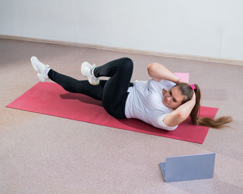 Full length of young woman exercising on floor