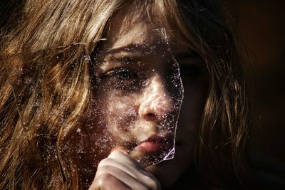 Close-up of thoughtful woman holding broken glass in darkroom