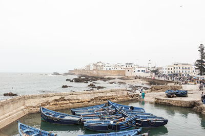 Boats moored on shore against clear sky