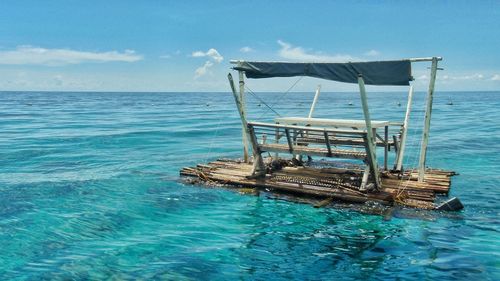 Abandoned chair on sea against blue sky