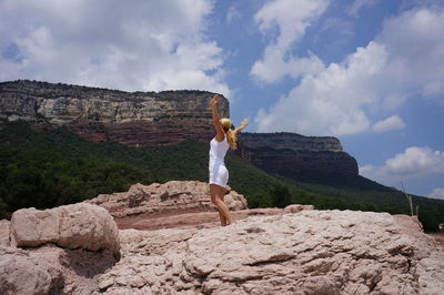 Man standing on rock against sky