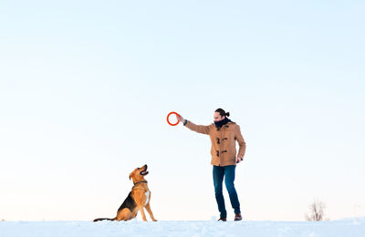 Full length of man with dog standing against sky