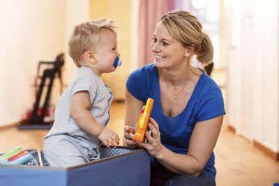Happy woman playing toys with baby boy at home