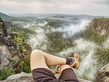 Low section of man standing on rock against waterfall