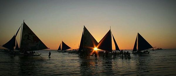 Boats in sea at sunset