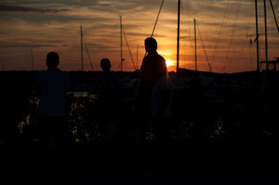 Rear view of silhouette people standing on land against sky during sunset