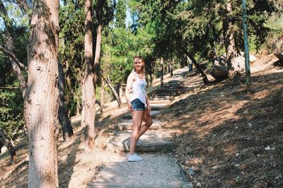 Young woman looking away while moving up on steps in forest