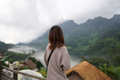 Rear view of man looking at mountain range against sky