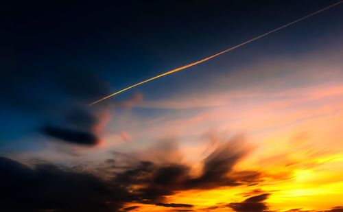 Low angle view of vapor trails in sky during sunset