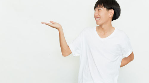 Smiling young woman standing against white background