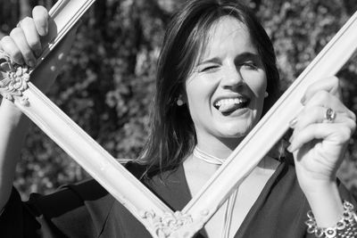 Portrait of young woman holding frame