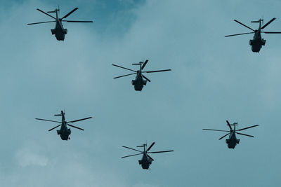 Low angle view of helicopters flying against sky