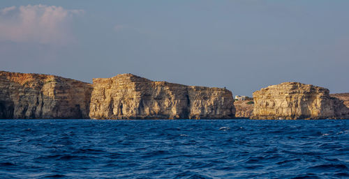 Rocky edges of the comino island sticking out from mediterranean sea and lit by the evening sun