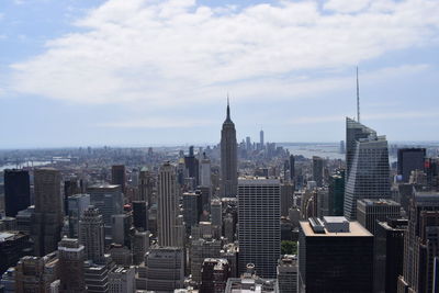 Aerial view of buildings in city against cloudy sky