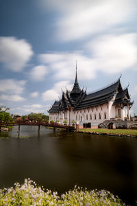 View of historic building by river against cloudy sky