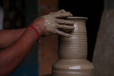 The potter works on a pottery wheel to made of soft colored clay, with hand and equipment