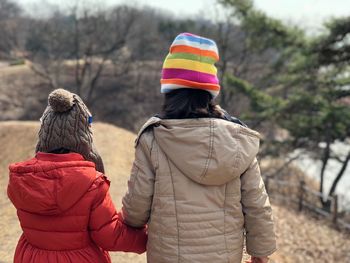 Rear view of siblings in warm clothing walking against trees