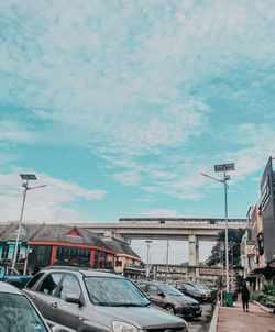 Cars on street by buildings against sky