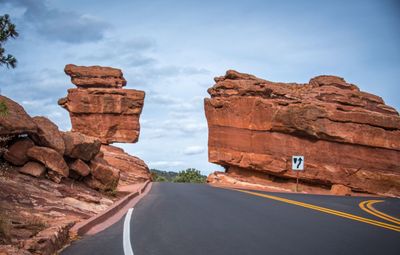 Rock formations by road against sky