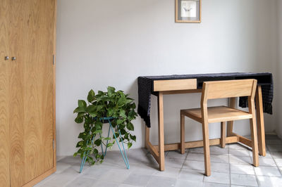 Wooden desk with chair, plants in the room, natural sunlight coming in, pasta tile floor, white