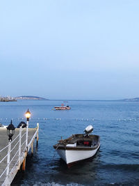 Boats moored in sea against clear sky