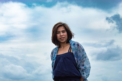 Portrait of beautiful young woman against sky