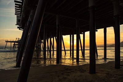 Silhouette pier on beach against sky during sunset