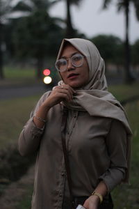 Portrait of woman wearing hijab while standing on field during sunset