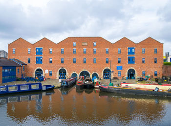 Canal by buildings against sky