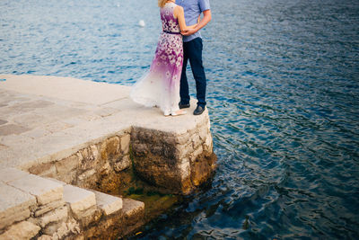 Low section of woman standing on rock by sea