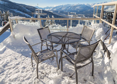 Empty chairs and tables on snow covered field