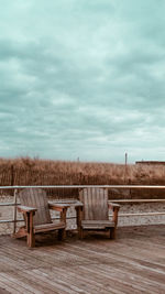 Empty chairs on beach against sky