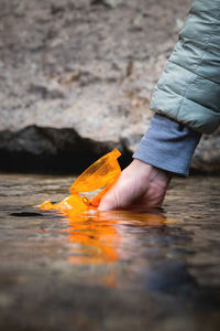 Close-up of female hands filling fresh cold water of a mountain stream into a reusable travel bottle