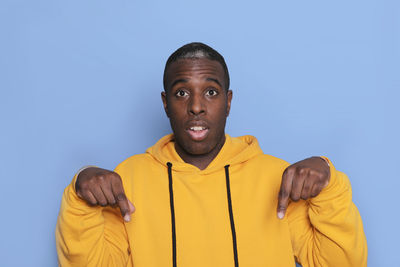 Portrait of man gesturing while standing against blue background