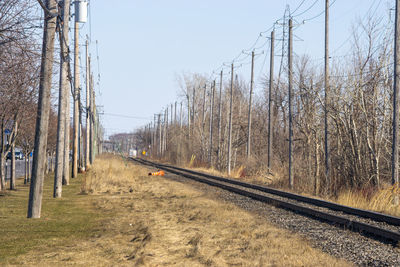 Railroad track amidst bare trees against clear sky