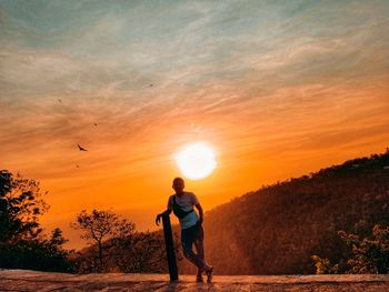 Full length of man standing against orange sky