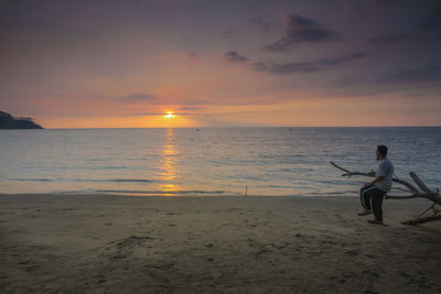 Man on beach against sky during sunset