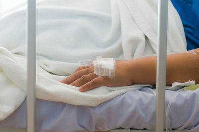 Midsection of woman with iv drip on bed at hospital