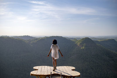 Rear view of man standing on mountain against sky