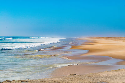 Scenic view of beach against clear blue sky