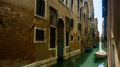 Buildings by canal against sky in city