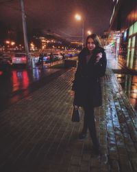 Portrait of smiling woman standing in illuminated city at night