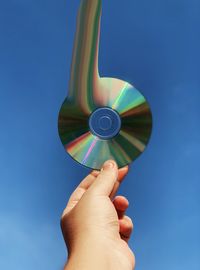 Low angle view of person hand against blue sky