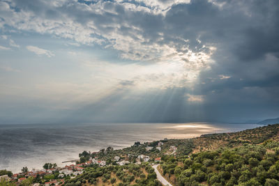 Scenic view of the aegean sea against dramatic sky with sun rays during storm on greece coastline