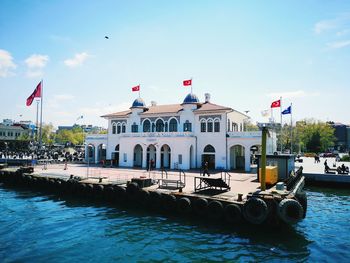 Boats in river by buildings against sky