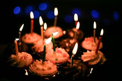 Close-up of birthday cake with illuminated candles at night