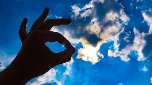 Low angle view of silhouette person hand against sky
