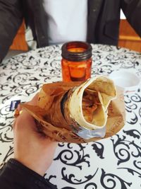 Close-up of hand holding drink on table
