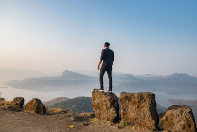 Man standing on rock against sky