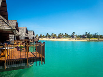 Swimming pool by sea against clear blue sky